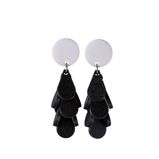 Black tiered earrings with white round tops on a white background